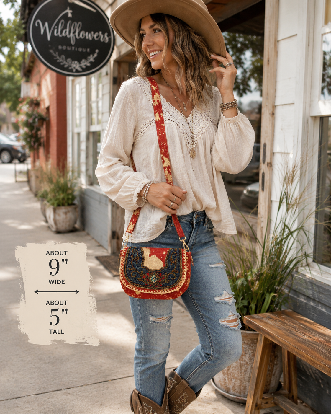 A woman stands on a storefront sidewalk wearing a cream blouse, blue jeans, brown boots, and a wide-brim tan hat, with a red beaded crossbody bag. A sign for Wildflowers Boutique is visible, and a text overlay notes the bag is about 9 inches wide by 5 inches tall.