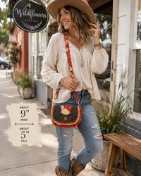 A woman stands on a storefront sidewalk wearing a cream blouse, blue jeans, brown boots, and a wide-brim tan hat, with a red beaded crossbody bag. A sign for Wildflowers Boutique is visible, and a text overlay notes the bag is about 9 inches wide by 5 inches tall.