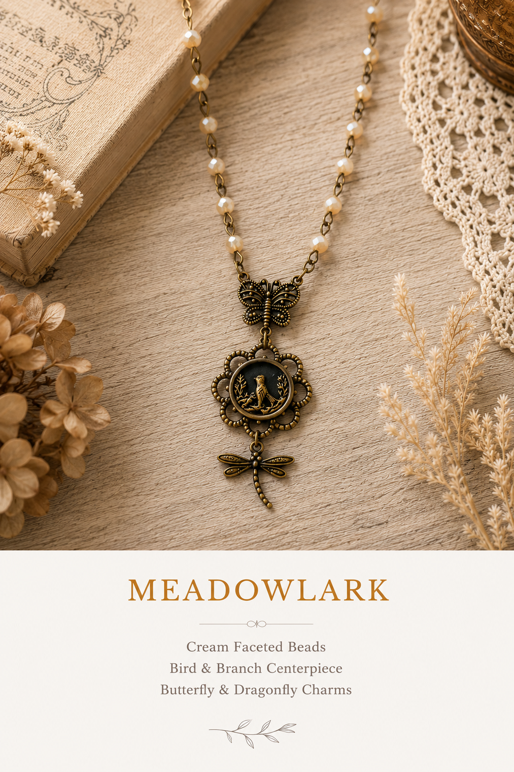 A bohemian-style necklace with cream faceted beads, an antique bronze butterfly and branch centerpiece, and dragonfly charms, displayed on a textured wood surface with dried flowers and a book. The bottom text panel reads 'MEADOWLARK'.
