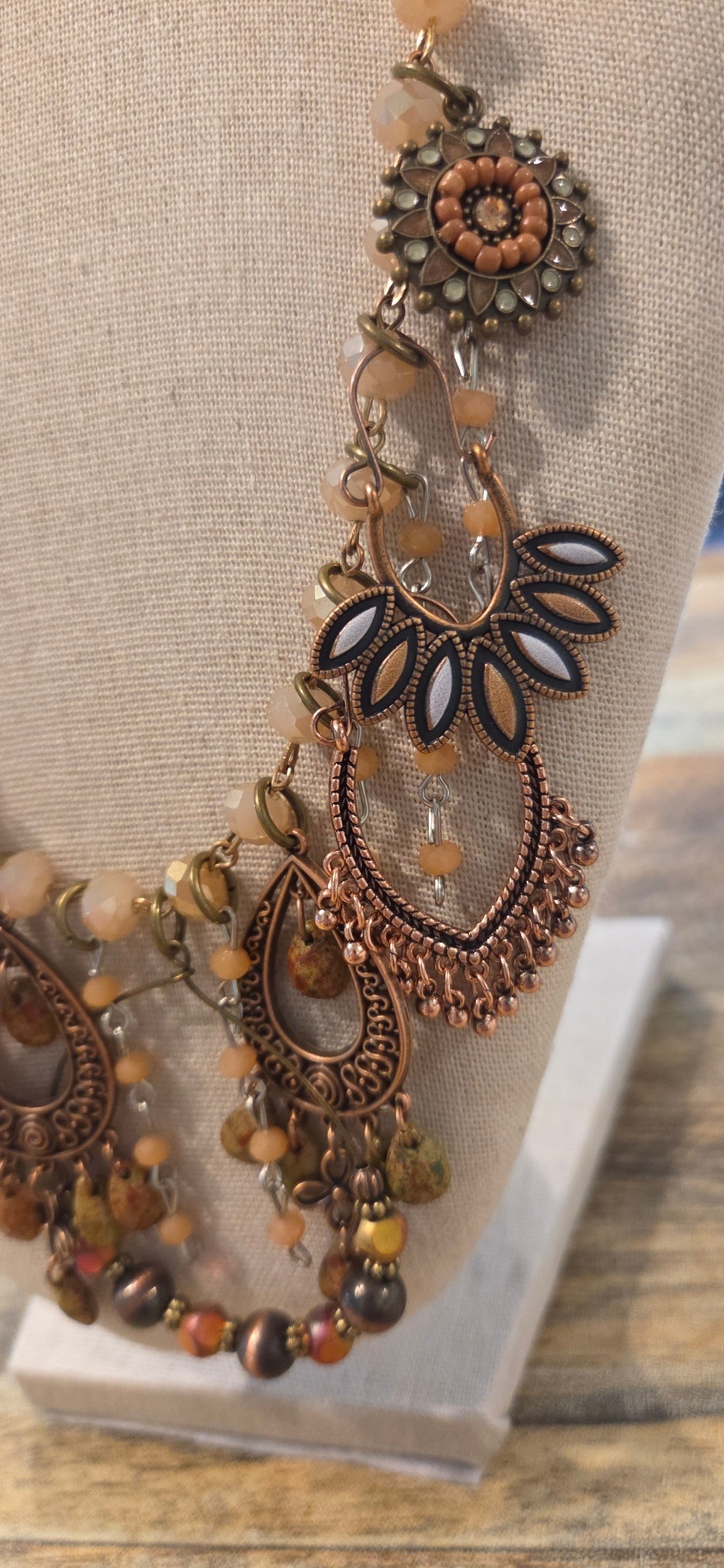 Close-up of copper tone boho necklace with ornate charms, beads and fringe details