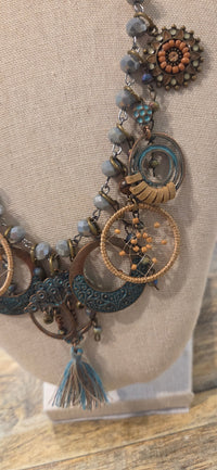Close-up of boho necklace with turquoise tone charms, gray beads and woven circle details