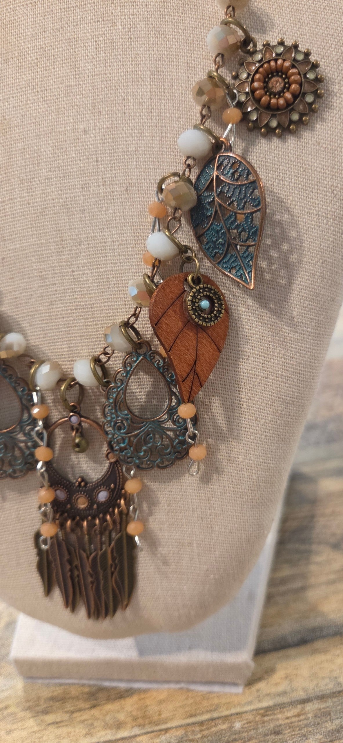 Close-up of handmade boho necklace with leaf charms, beads and antiqued metal details