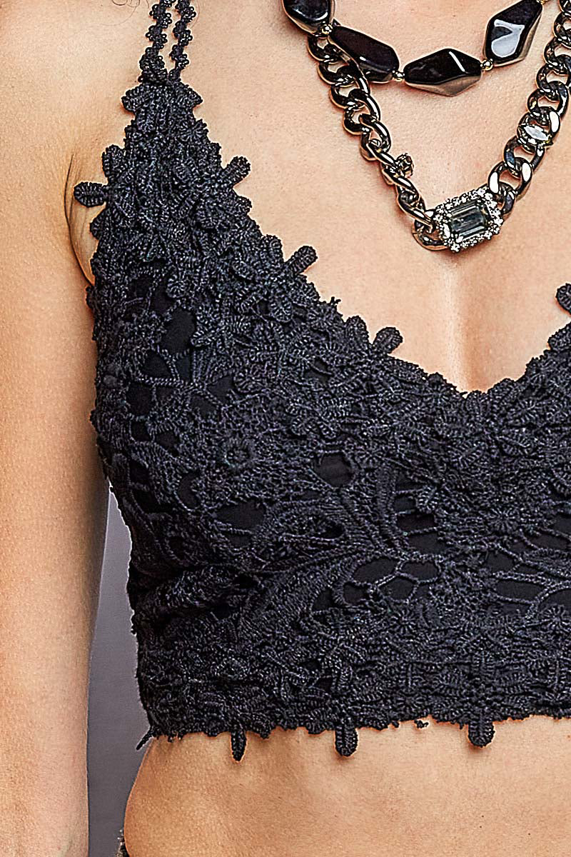 Close-up of a model wearing a black lace halter crop top with textured floral lace detailing, paired with a chunky silver chain necklace.