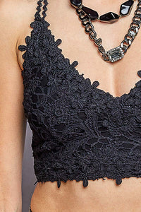 Close-up of a model wearing a black lace halter crop top with textured floral lace detailing, paired with a chunky silver chain necklace.