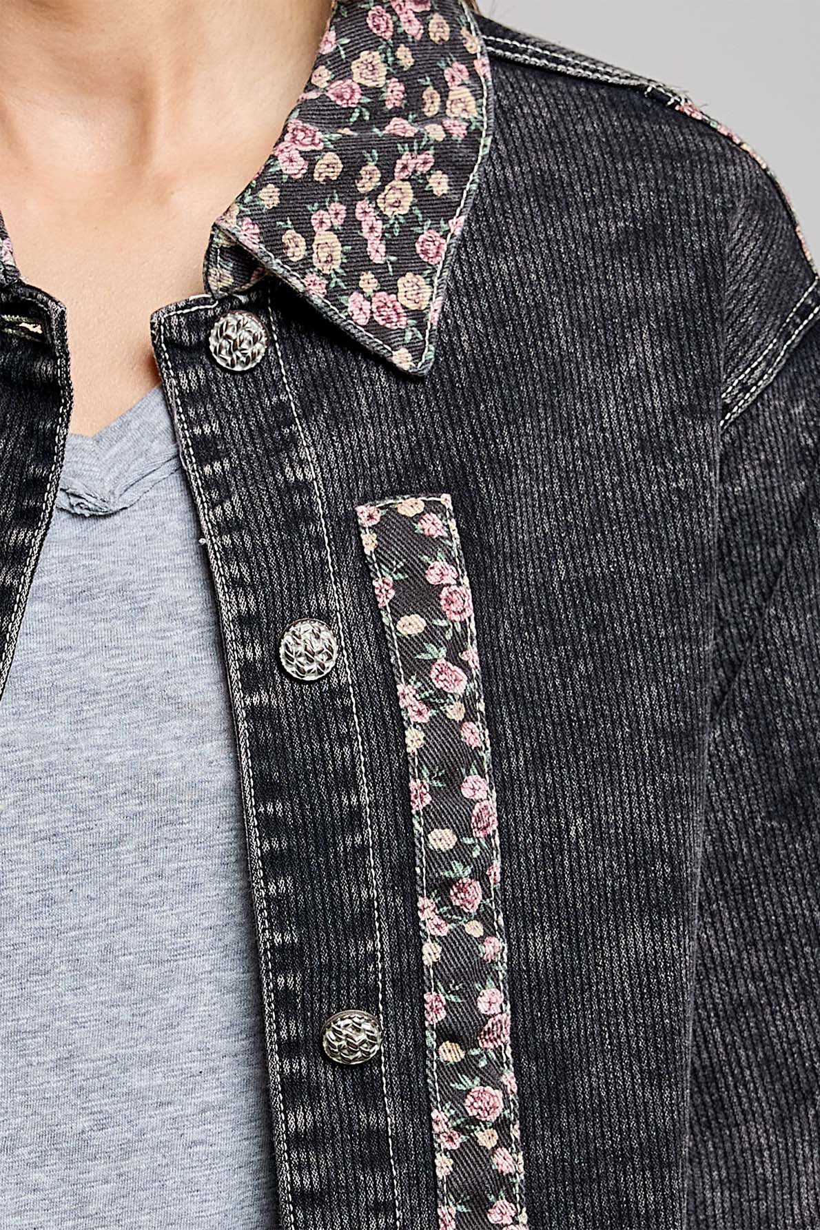 Close-up of a person wearing a dark washed denim jacket with floral patterned inner collar and pocket lining over a light gray t-shirt.