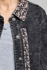 Close-up of a person wearing a dark washed denim jacket with floral patterned inner collar and pocket lining over a light gray t-shirt.
