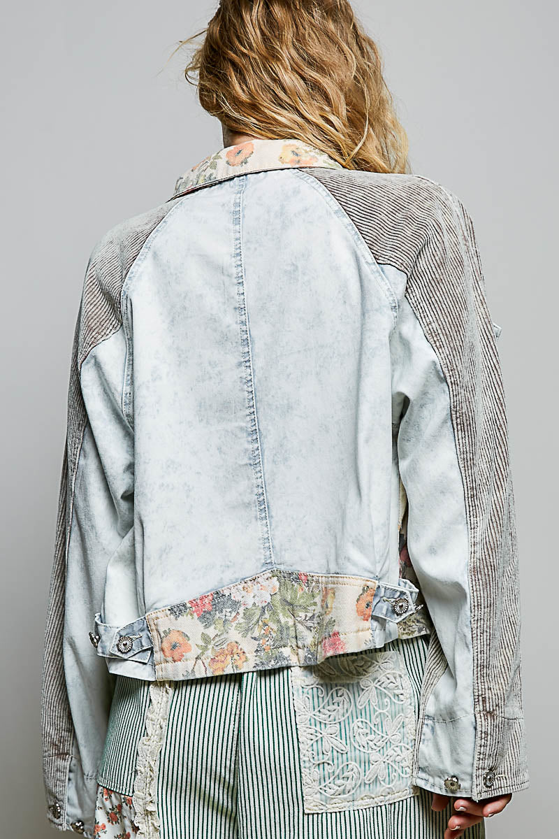 Light blue denim jacket with floral embroidery on a gray background