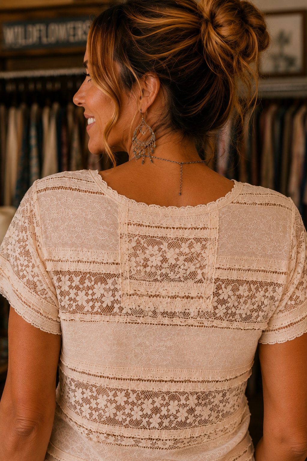 A woman shown from the back wearing a cream-colored short-sleeve blouse with intricate lace and floral embroidery patterns across the back and shoulders.