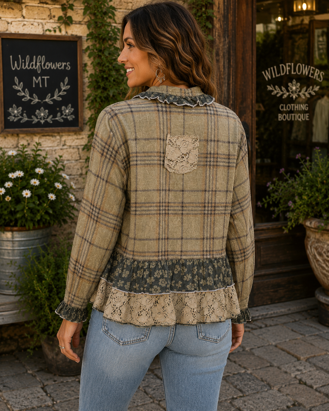 A woman wearing a beige and brown plaid long-sleeve blouse with lace ruffle trim and a floral patch pocket on the back, standing outdoors in front of a boutique storefront.