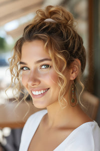 Woman with styled hair and earrings smiling outdoors
